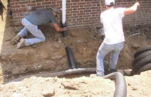 Building water intrusion can be stopped on the exterior by installing a French drain around the perimeter of the building to intercept the water and carry it away from the foundation.